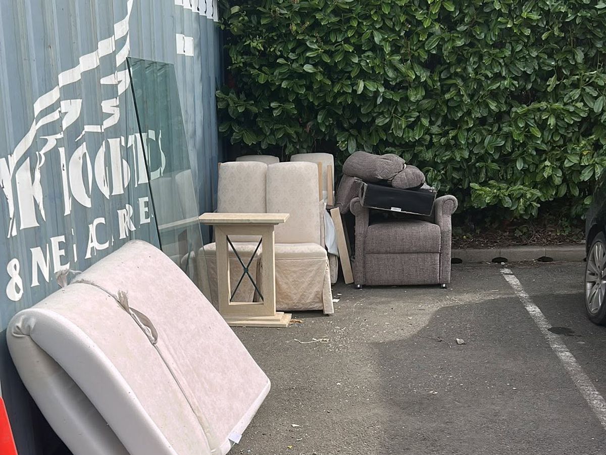 Fly tipped armchairs, mattress and side table dumped in a Birmingham car park before removal
